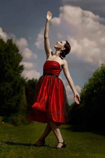 Lady in red dress posing in garden — Stock Photo, Image