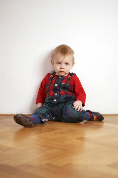 Jeune garçon jouant à l'intérieur sur le sol en bois — Photo