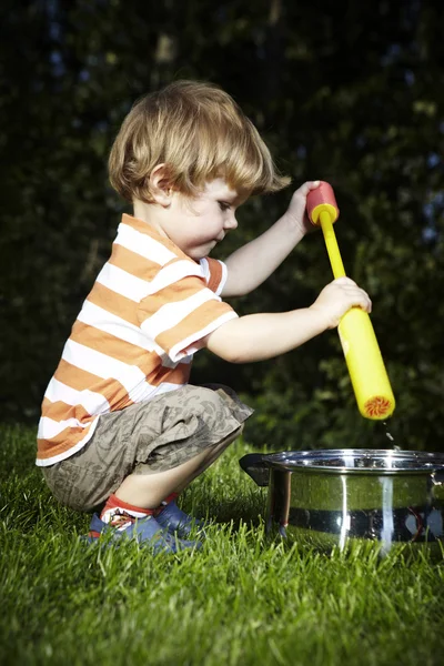 Jonge jongen thuis spelen in de buurt van huis in tuin met verschillende speelgoed — Stockfoto