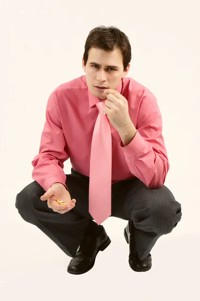 Man in pink shirt eating pills for headache — Stock Photo, Image