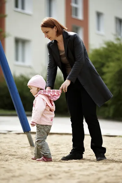 Petite fille dehors sur une aire de jeux jouant avec sa mère — Photo