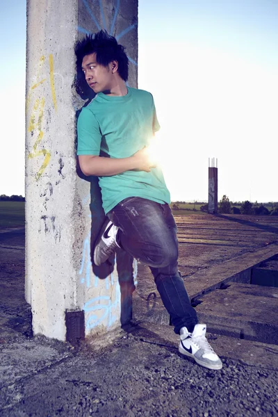 Unga asiatiska pojken posingfor eleganta bilder i ruinerna av byggnaden — Stockfoto