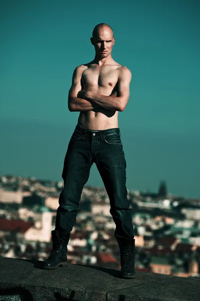 Hombre de ciudad posando en la parte superior de la pared ingenio ciudad panorama detrás de — Foto de Stock