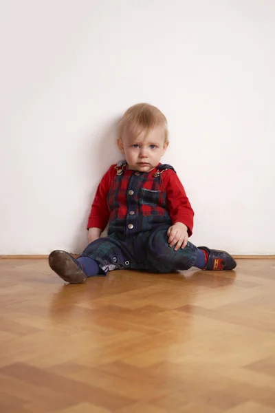 Mladý chlapec hraje vnitřní na dřevěnou podlahu — Stock fotografie