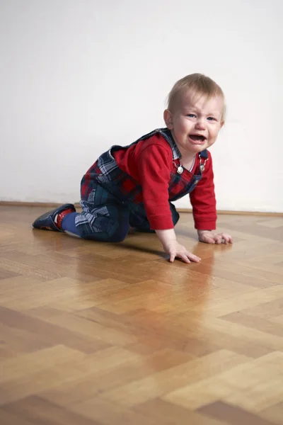 Jeune garçon jouant à l'intérieur sur le sol en bois — Photo