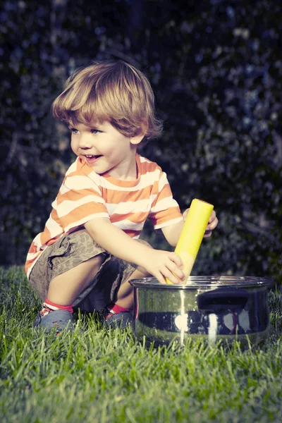 Ung pojke spelar hemma nära house i trädgård med olika leksaker — Stockfoto