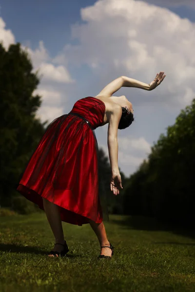 Signora in abito rosso in posa in giardino — Foto Stock