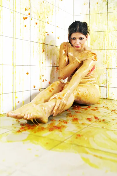 Молодая женщина играет с расплавленным желе в белой комнате плитки — стоковое фото