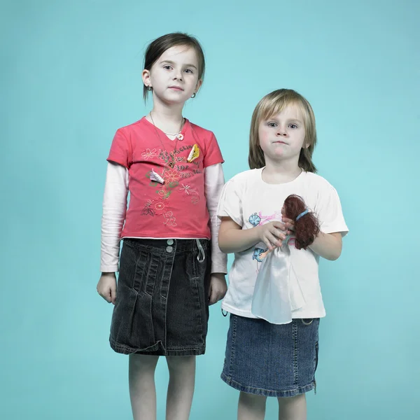 Two girls posing in studio on blue background — Stock Photo, Image