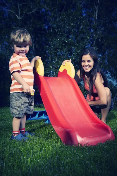 Giovane ragazzo che gioca a casa vicino a casa in giardino con sua madre con vari giocattoli — Foto Stock