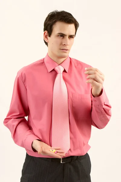 Homem de camisa rosa comendo pílulas para dor de cabeça — Fotografia de Stock