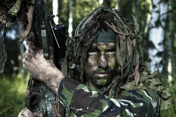Скрытый солдат спецназа со снайперской винтовкой наблюдает местность в естественных лесных пейзажах — стоковое фото