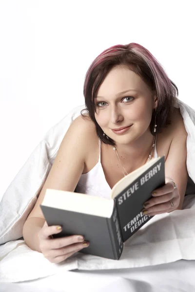 Menina na cama lendo um livro — Fotografia de Stock