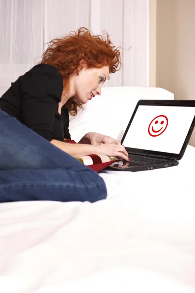 Senhora no quarto com notebook trabalhando e navegando na internet — Fotografia de Stock