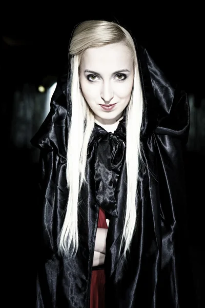 Blondes Mädchen posiert in einem schwarzen Mantel — Stockfoto