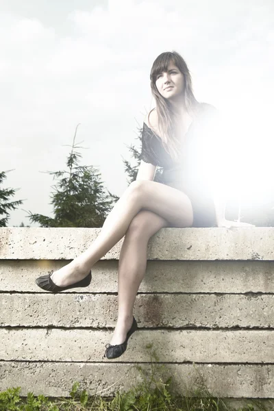 Brunette girl sitting on a concrete slab — Stock Photo, Image