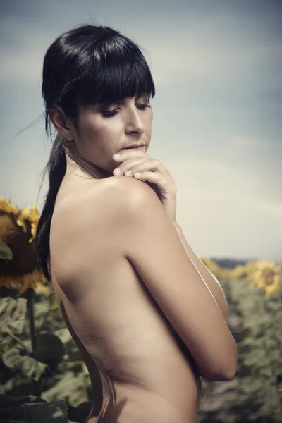 Nackte Brünette Mädchen in einem Feld von Sonnenblumen — Stockfoto