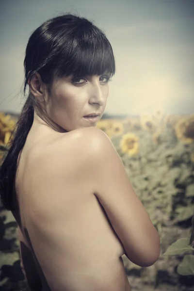Naakt brunette meisje in een veld met zonnebloemen — Stockfoto