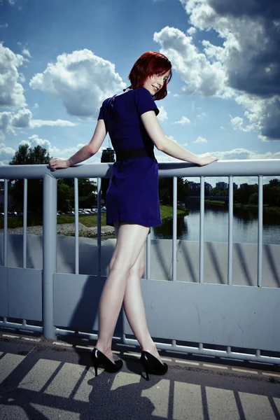 Redhead in blue posing in summer light on floodgate — Stock Photo, Image