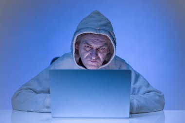 Older criminal man using computer for remote money robbery clipart
