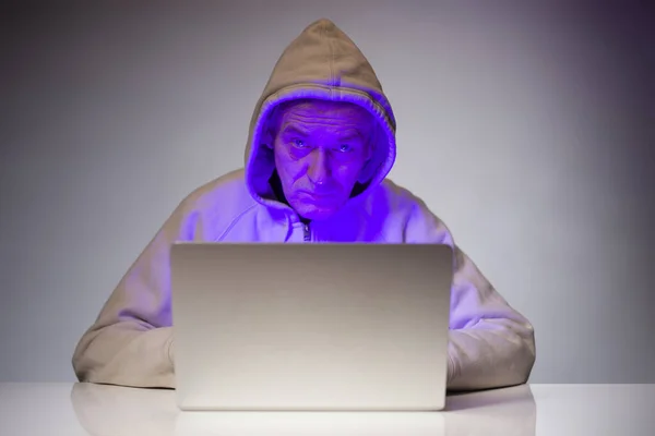 Older criminal man using computer for remote money robbery