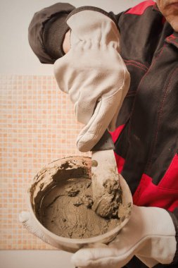 Older man working in empty apartment repairing holes in walls