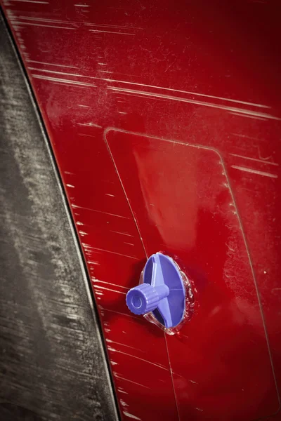 Car owner working on a dent repair with reverse hammer and glue