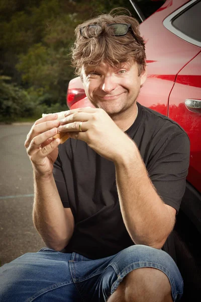 マイナーな車の修理作業後にサンドイッチを食べる車の運転手 — ストック写真