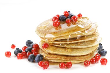 Small pancakes topped with honey, red currants and bilberries