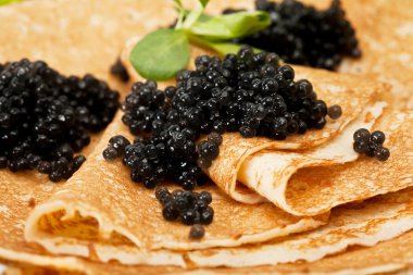 Pancakes with black caviar and greens