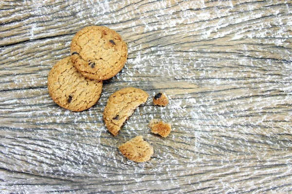 round chocolate chip cookie with crumbs on wood table background