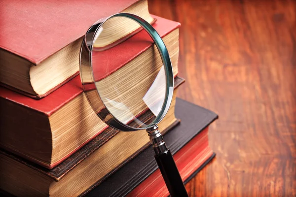 Magnifying glass with old books — Stockfoto