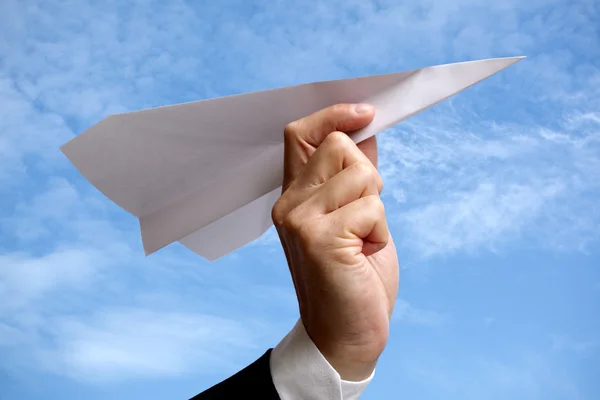 Деловой человек с бумажным самолетом против голубого неба — стоковое фото