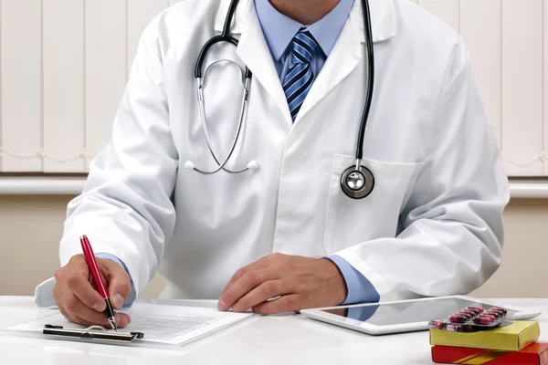 Médico que escreve uma prescrição ou notas de exame médico — Fotografia de Stock