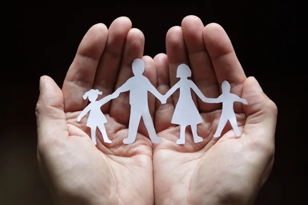 Paper chain family protected in cupped hands — Stock Photo, Image