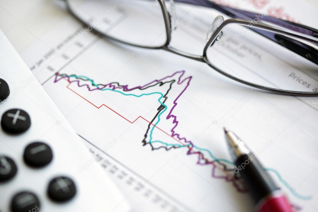 Pen glasses and calculator on stock chart