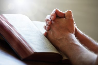 Praying hands on a Holy Bible