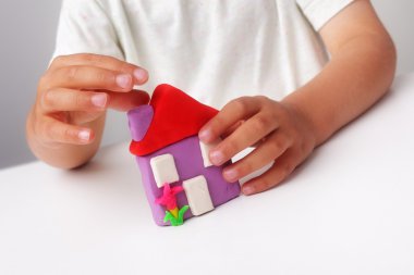 Child buiding a play clay house clipart