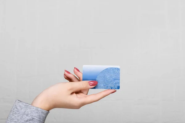 Mano femminile in possesso di una carta di credito blu su uno sfondo muro — Foto Stock