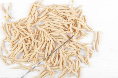 Beyaz ahşap bir masada, Pizzarieddi ya da Maccaruni adında tam tahıllı apulian makarnası. Taze Maccheroni tipik Puglia yemeği, Salento İtalya. İtalyan ev yapımı makarna arka planı