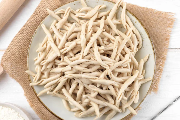 白木製のテーブルの上のセラミックプレート上のPizzarieddiまたはmaccaruni(ピザリーディ)と呼ばれる全粒小麦生のアプリリアンパスタ — ストック写真