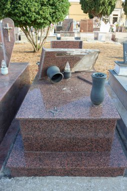 A broken gravestone made of granite, a desecrated grave, a profanation of a cemetery, Italy