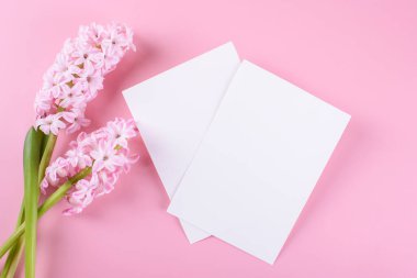 Two blank wedding invitation stationery card mockup on pink background with hyacinth flowers, feminine blog flat lay, top view. Minimalist mockup 5x7 ratio, similar to A6, A5