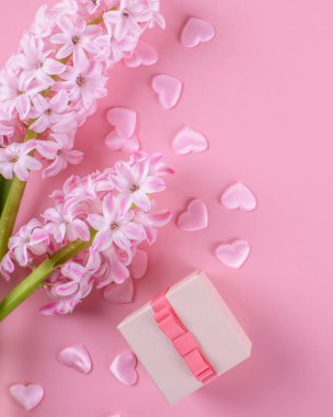 Gift or present box, beautiful pink hyacinth flowers and pink hearts on pink table top view. Flat lay composition for Valentines day, birthday, mother day or wedding, monochrome