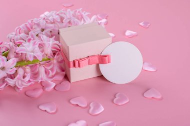Blank stationery gift tag mockup, thank you tag or favor tag with gift box on pink background with hyacinth flowers and pink hearts. Valentines day card, valentines day background, mothers day