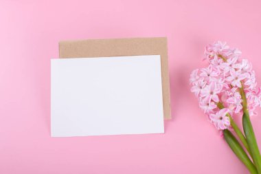 Blank wedding invitation stationery card mockup with envelope on pink background with hyacinth flowers