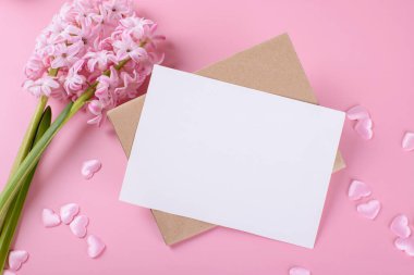 Blank wedding invitation stationery card mockup with envelope on pink background with hyacinth flowers and pink heart