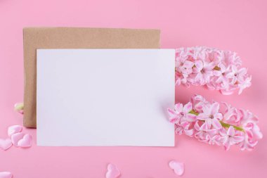 Blank wedding invitation stationery card mockup with envelope on pink background with hyacinth flowers and pink heart