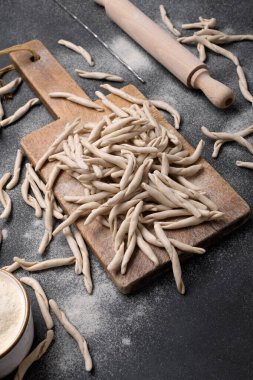 Pizzarieddi ya da Maccaruni adında tam tahıllı apulian makarnası siyah masanın üzerinde. Taze Maccheroni tipik Puglia yemeği, Salento İtalya. İtalyan ev yapımı makarna arka planı, kapat