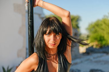 Genç ve güzel bir striptizci direğin üzerinde poz veriyor. Yazın gün batımında açık hava tekniği eğitimi. Yazın dışarıda Polonyalı dansçı eğitimi, herkes için spor..